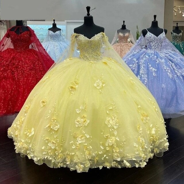 A woman in a pastel yellow quinceanera dress with a sweetheart neckline, 3D floral embellishments, and a cap sleeve.