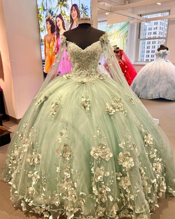Green ball gown with floral details on a mannequin in a store setting.