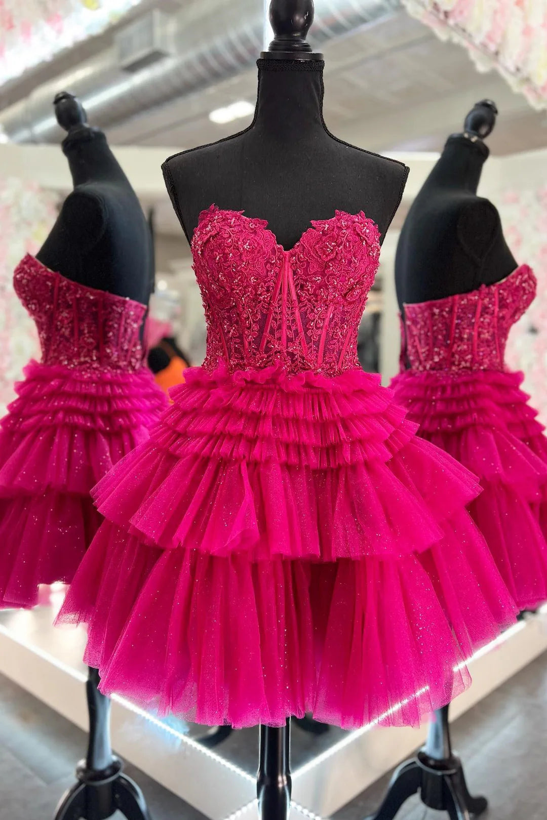 Hot pink homecoming dress on a mannequin with a blurred store background